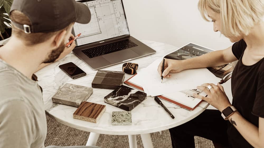 Two designers collaborating on a project with drafting materials