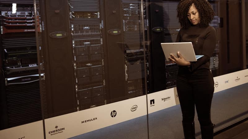 Engineer with a tablet working between server racks
